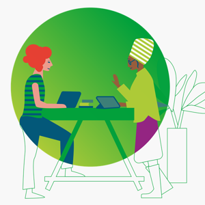 Two individuals at a table, each using a laptop, engaged in a collaborative work session.